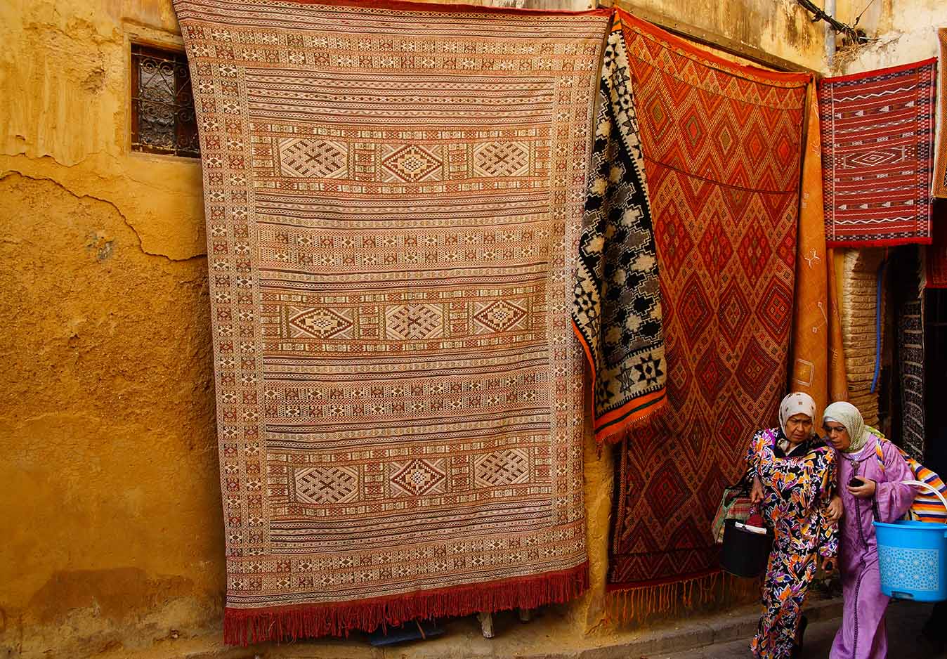 twee vrouwen in een straat met tapijten in Fes