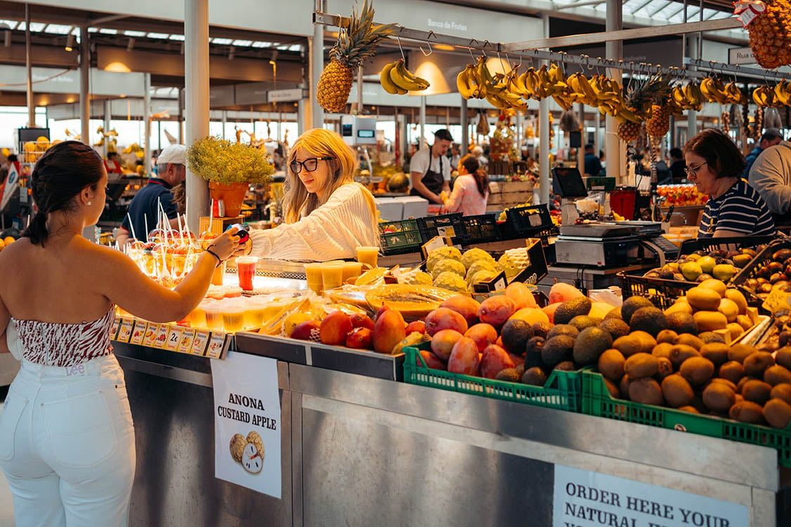 vrouw koopt vers fruitsap op de markt in Porto