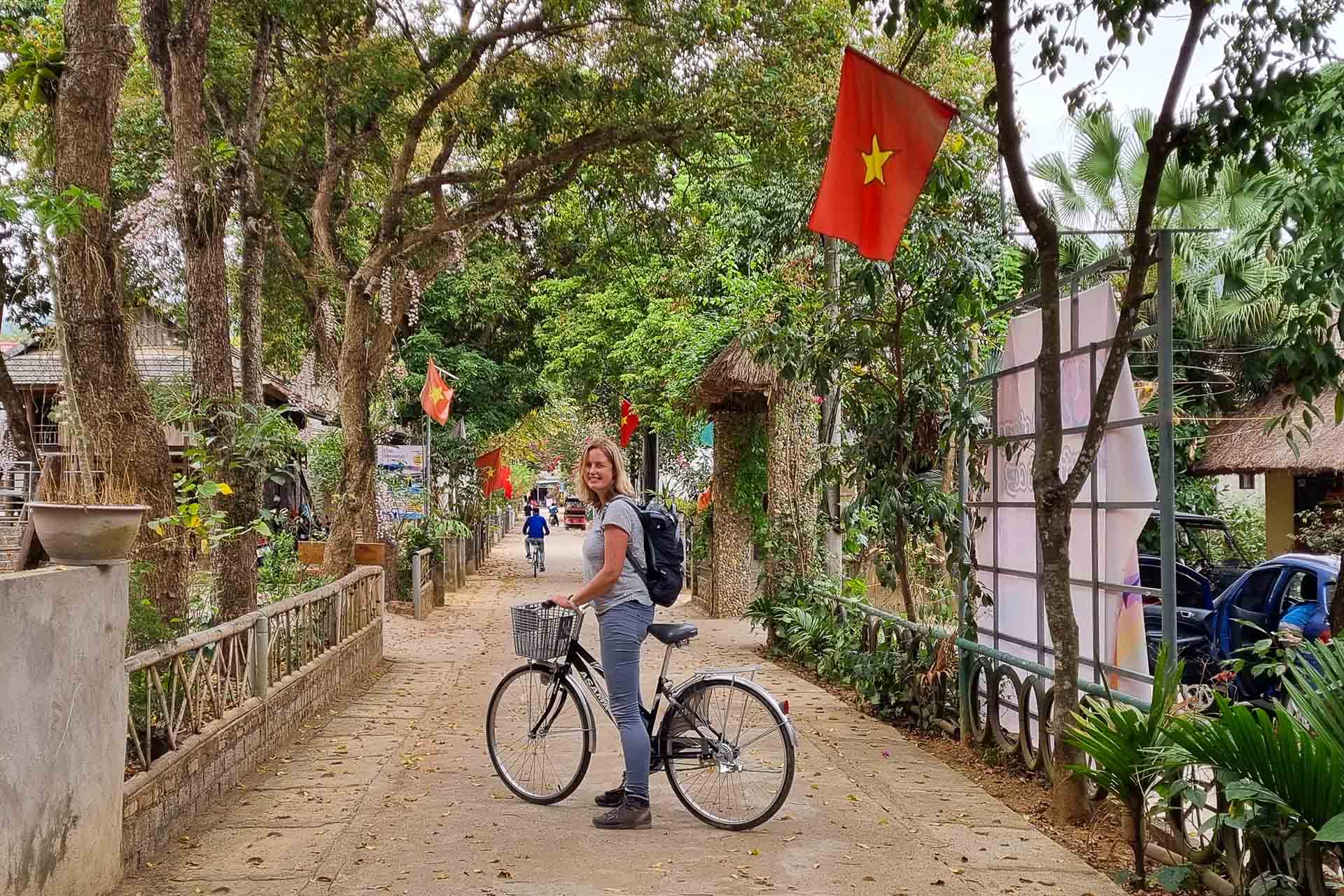 vrouw op fiets in een straat in Vietnam met Vietnamese vlag