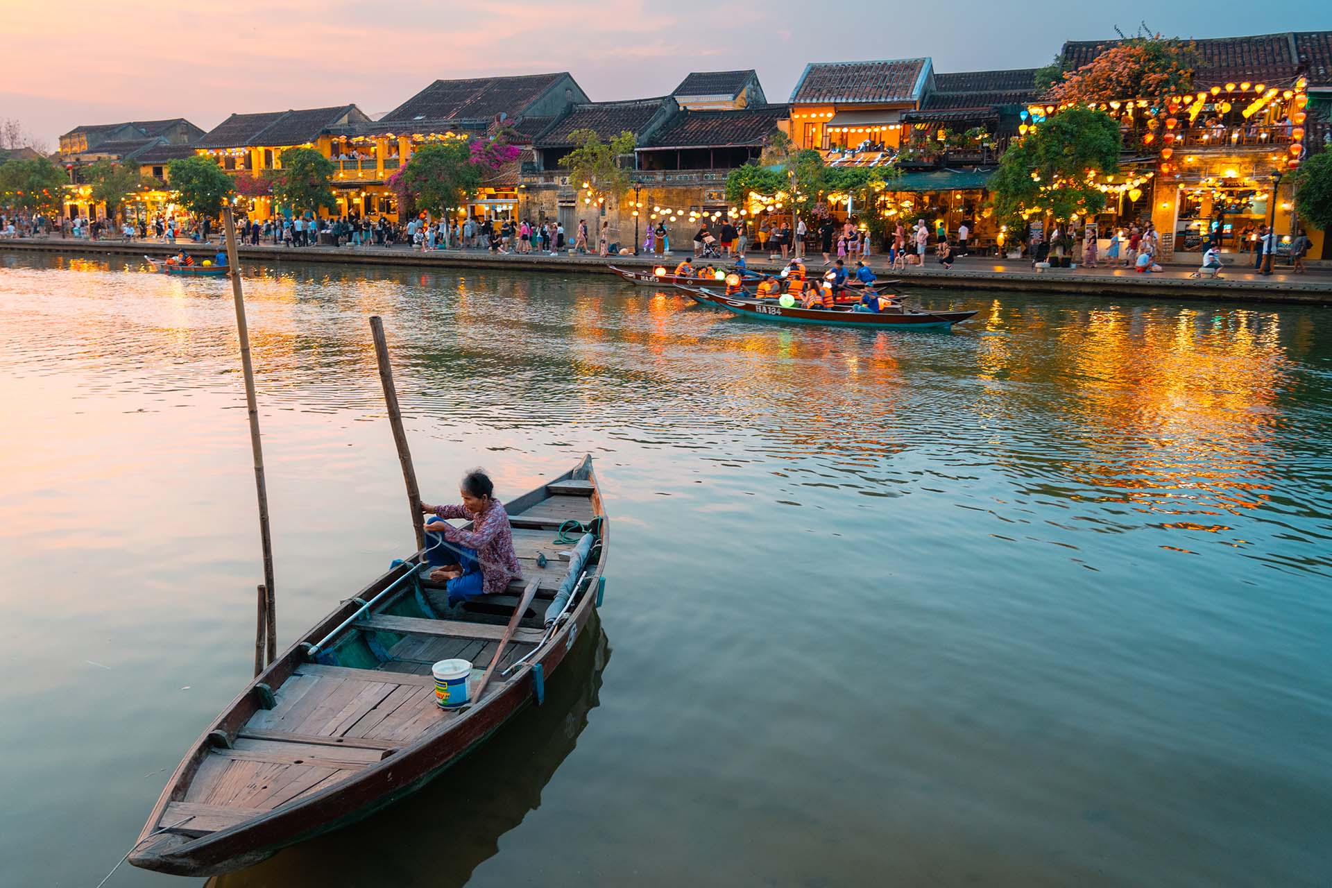 bootje met oude dame op de rivier in Hoi An met op de achtergrond Chinese huizen