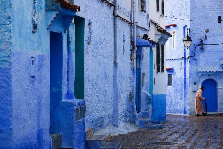 blauwgeschilderde huizen in Chefchaouen en een gebogen man in traditionele kleding