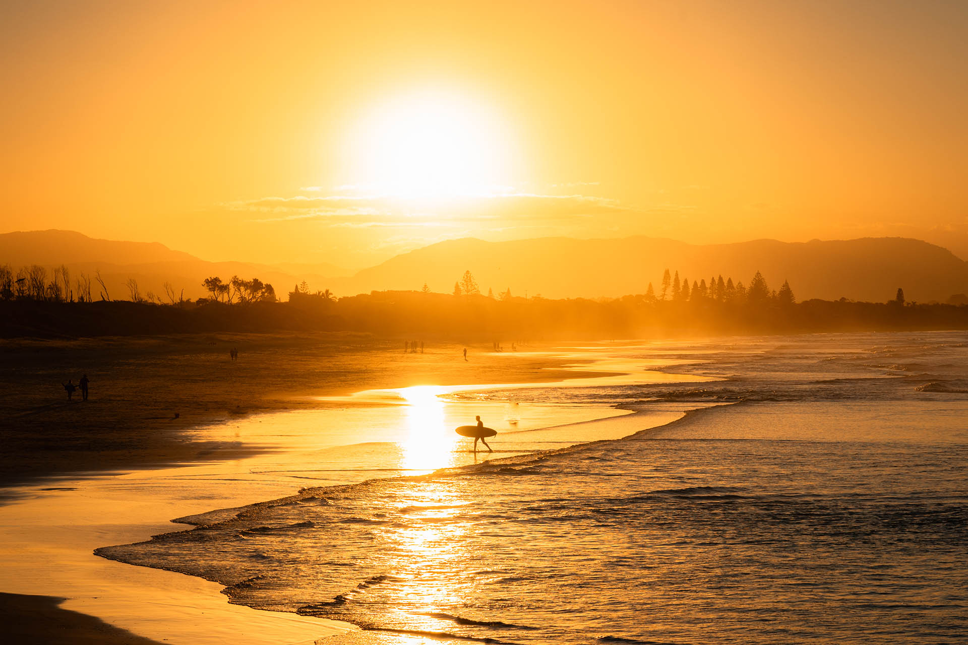 surfer loop de zee uit bij zonsondergang Byron Bay