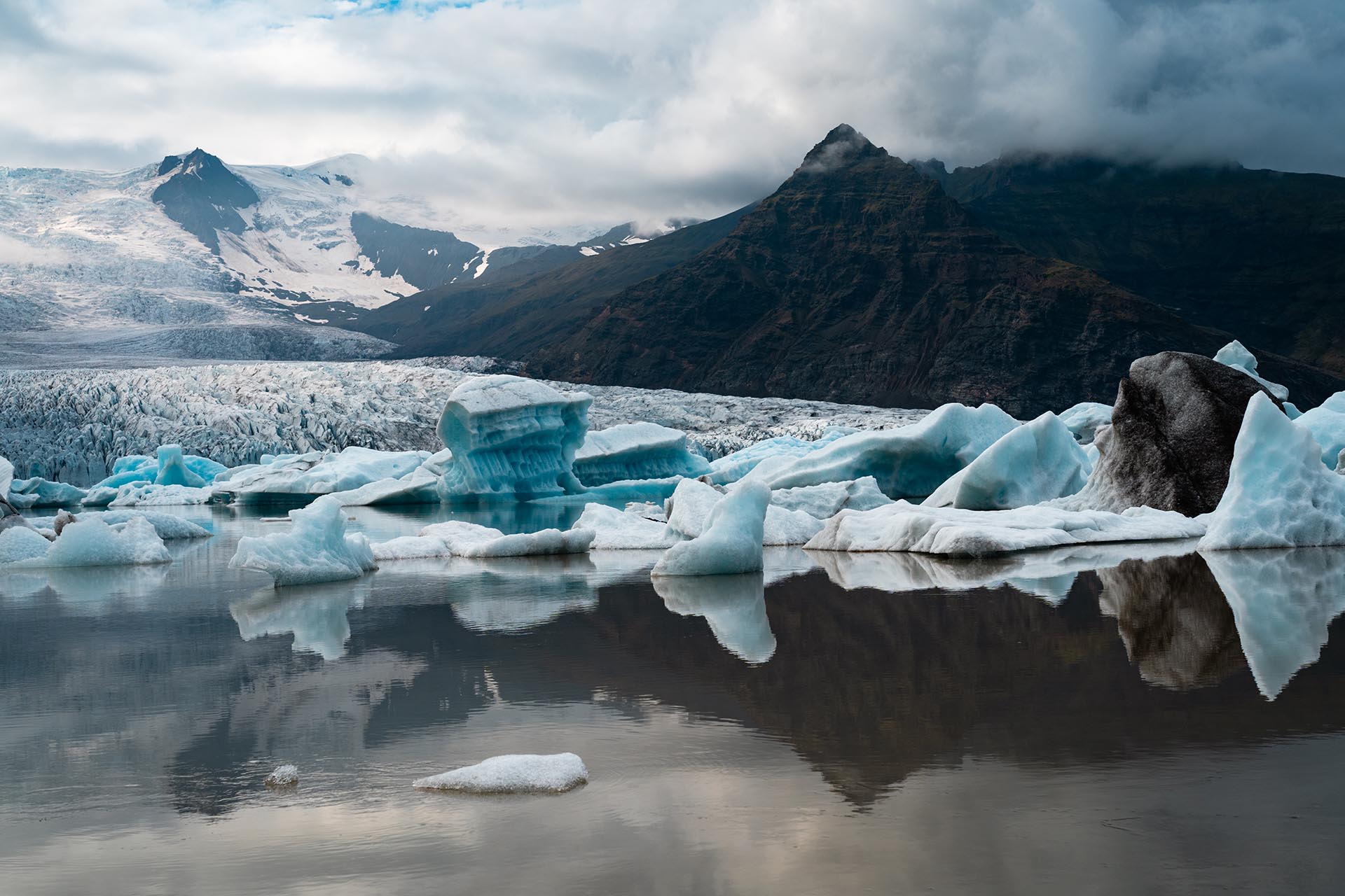 drijvende ijsschotsen in een meer met gletsjer en bergen op de achtergrond