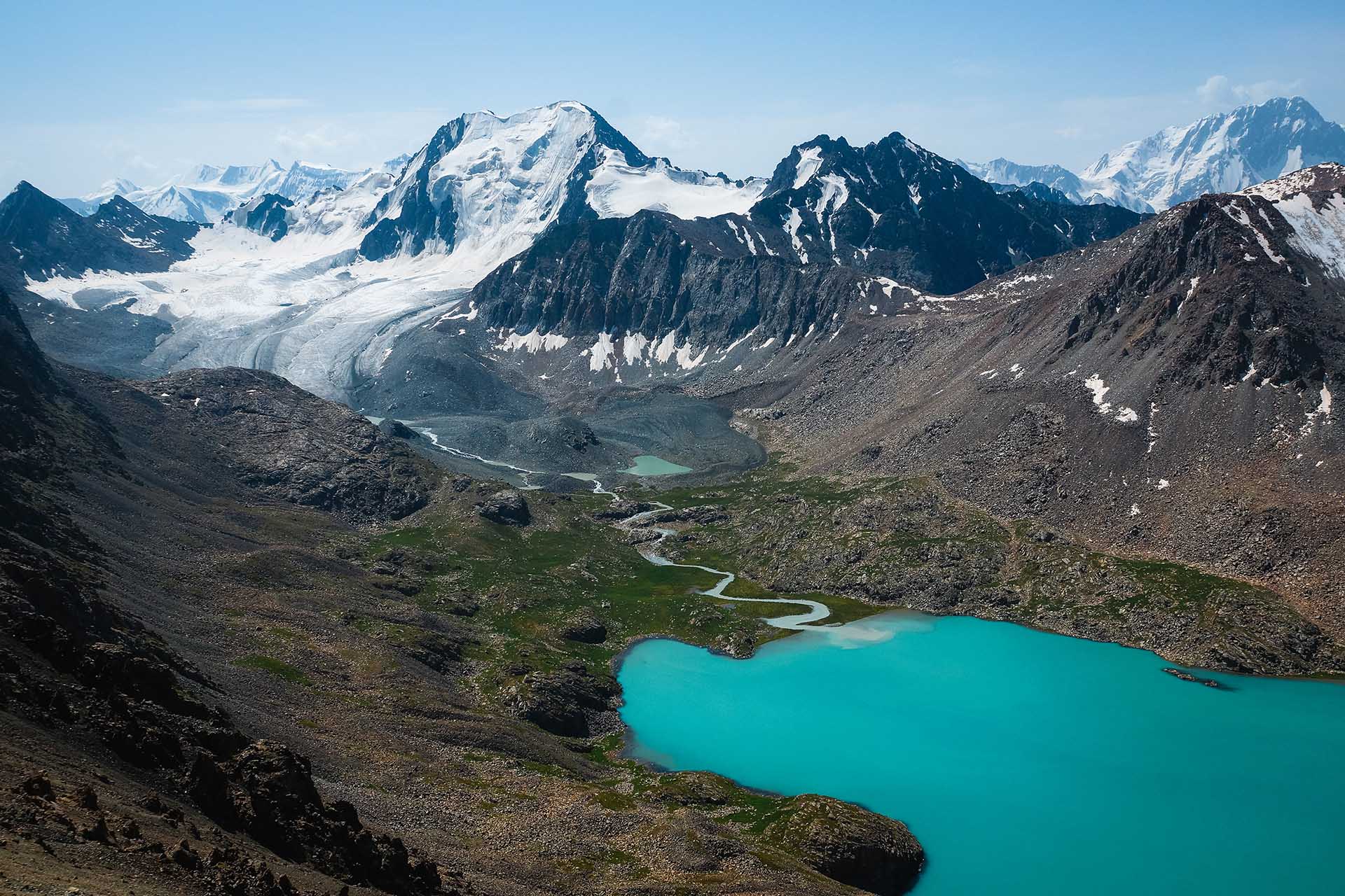 turquoise bergmeer omringd door besneeuwde bergen Kirgizië