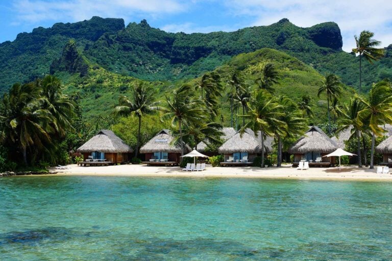 De bergen en lagoon van Moorea met huisjes op het strand