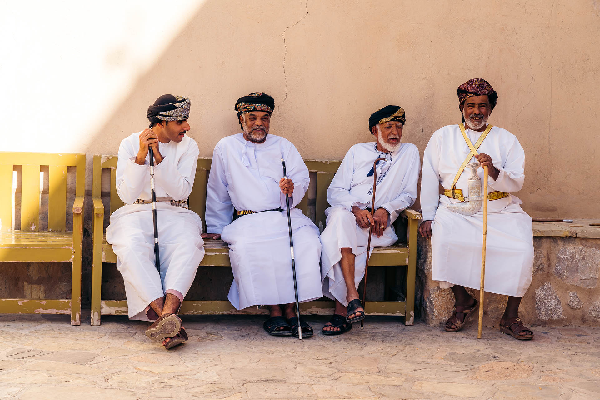 vier traditioneel geklede mannen in Oman op een bankje