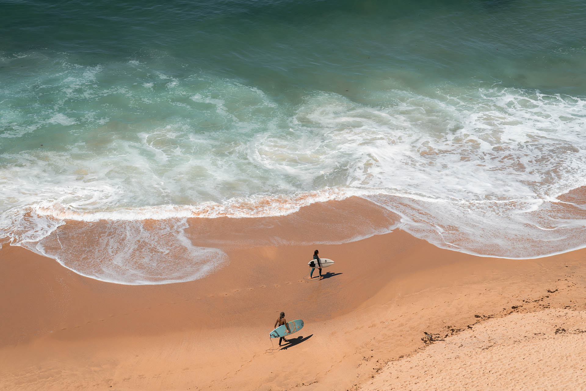 twee surfers op het strand van bovenaf gezien