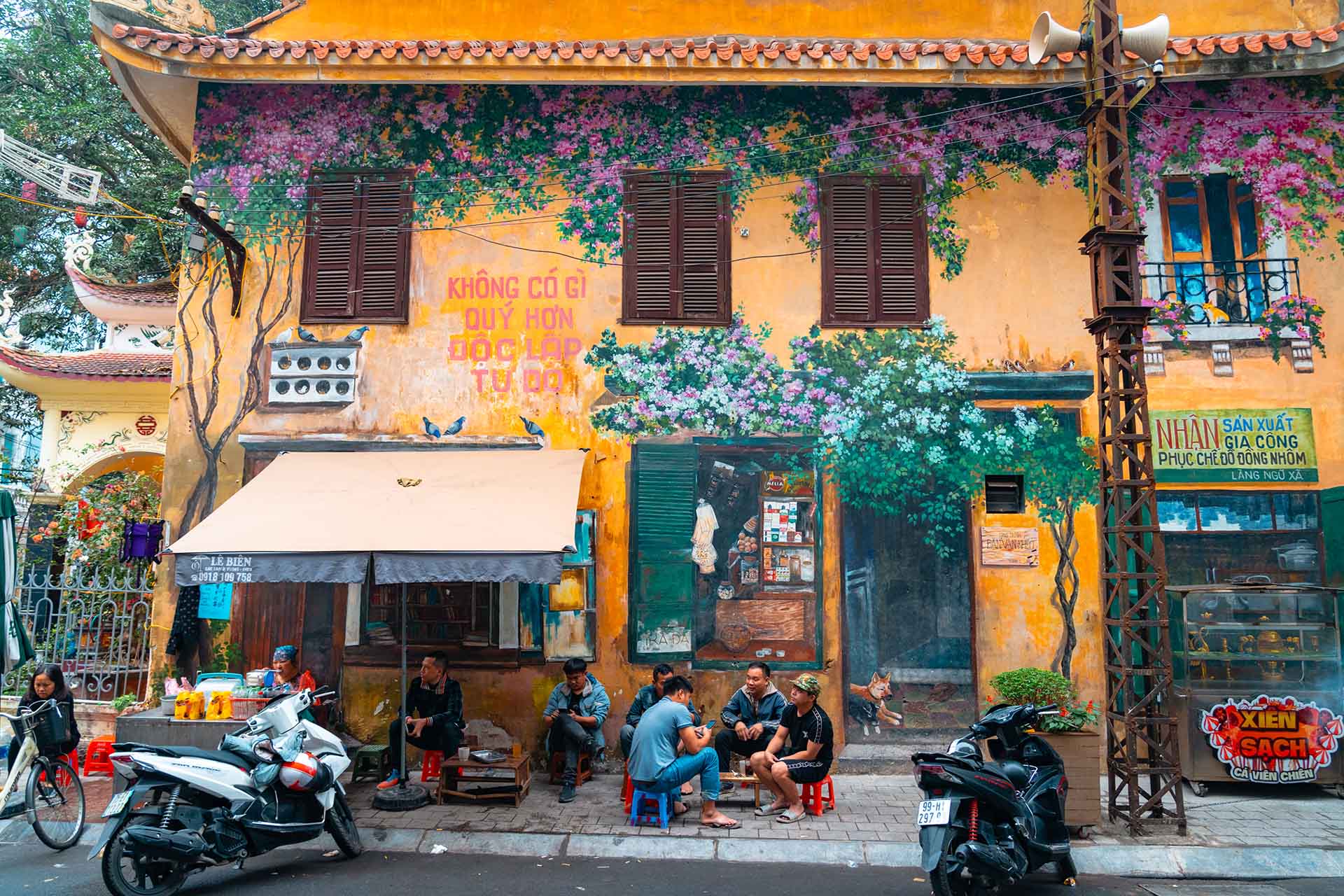 Beschilderd huis in Hanoi met straatstalletje en eters op lage plastic stoeltjes