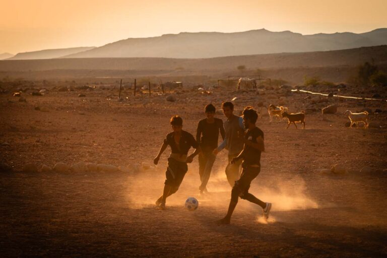 Voetballende jongens bij zonsondergang in Jordanië