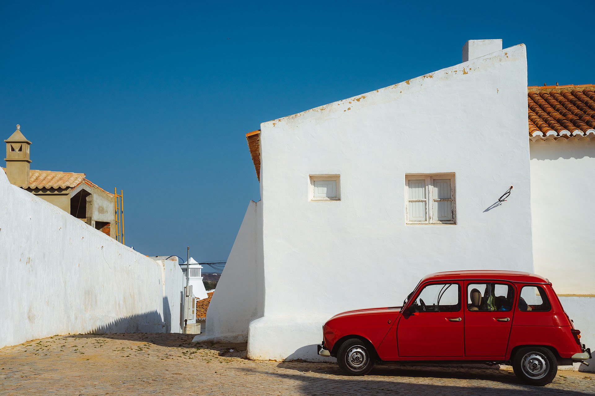 rode auto bij witte gebouwen Portugal