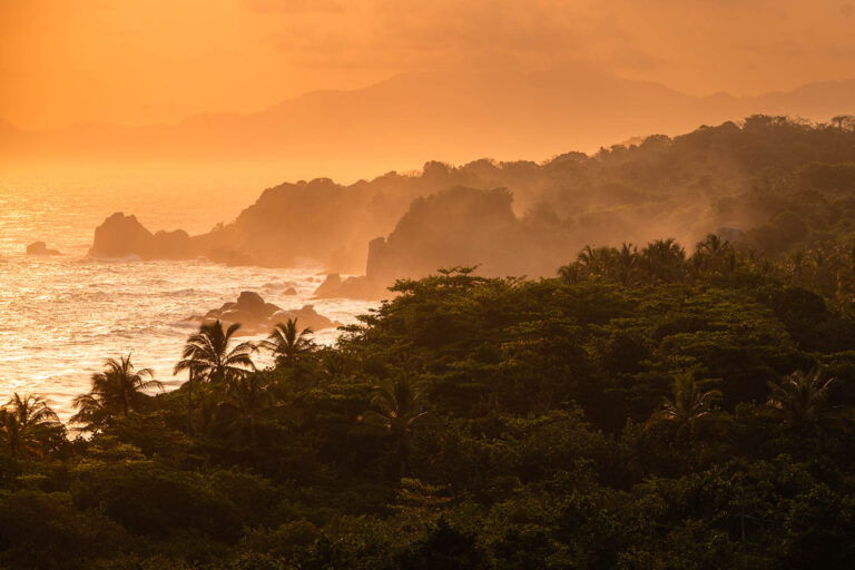 zonsondergang boven zee met bergen en jungle