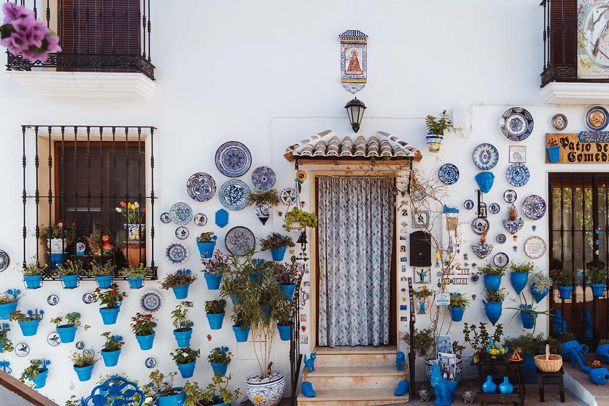witte gevel huis met blauwe bordjes en bloempotten